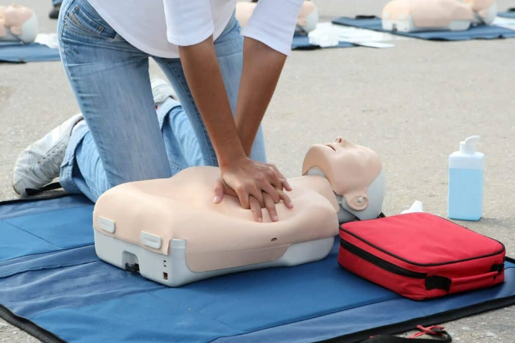 First aid trainee performing CPR on dummy.