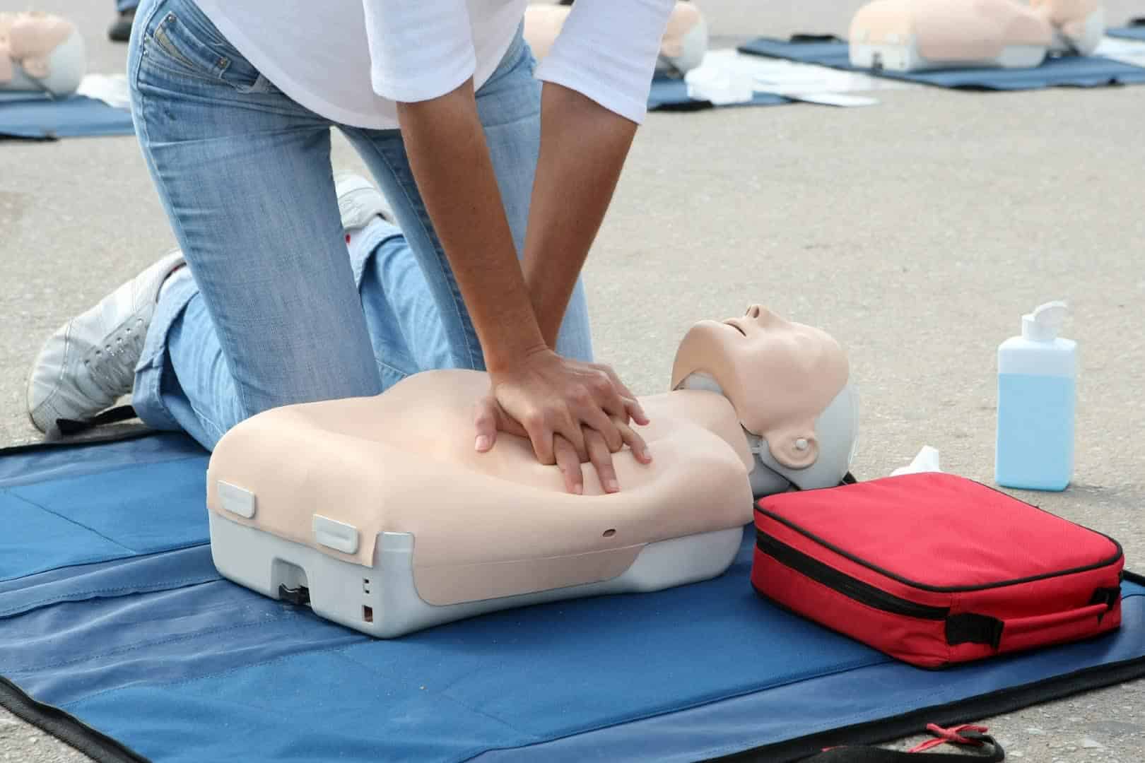 First aid trainee performing CPR on dummy.