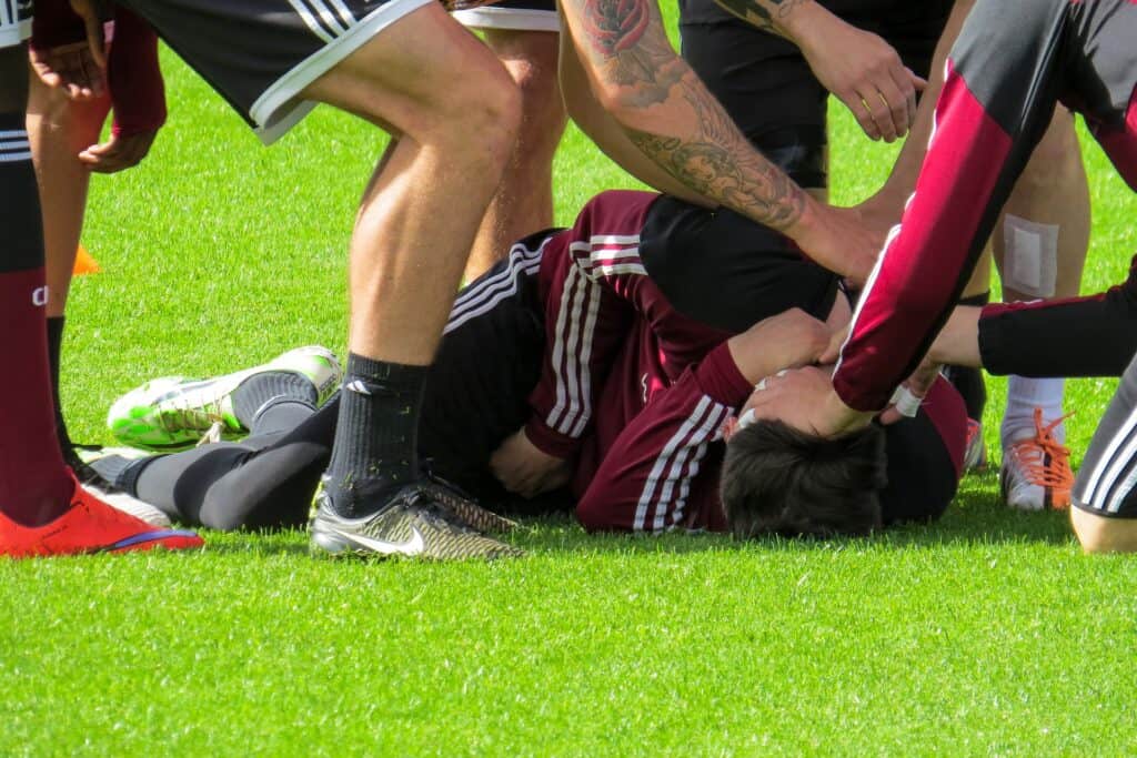 Players assisting injured player on field.